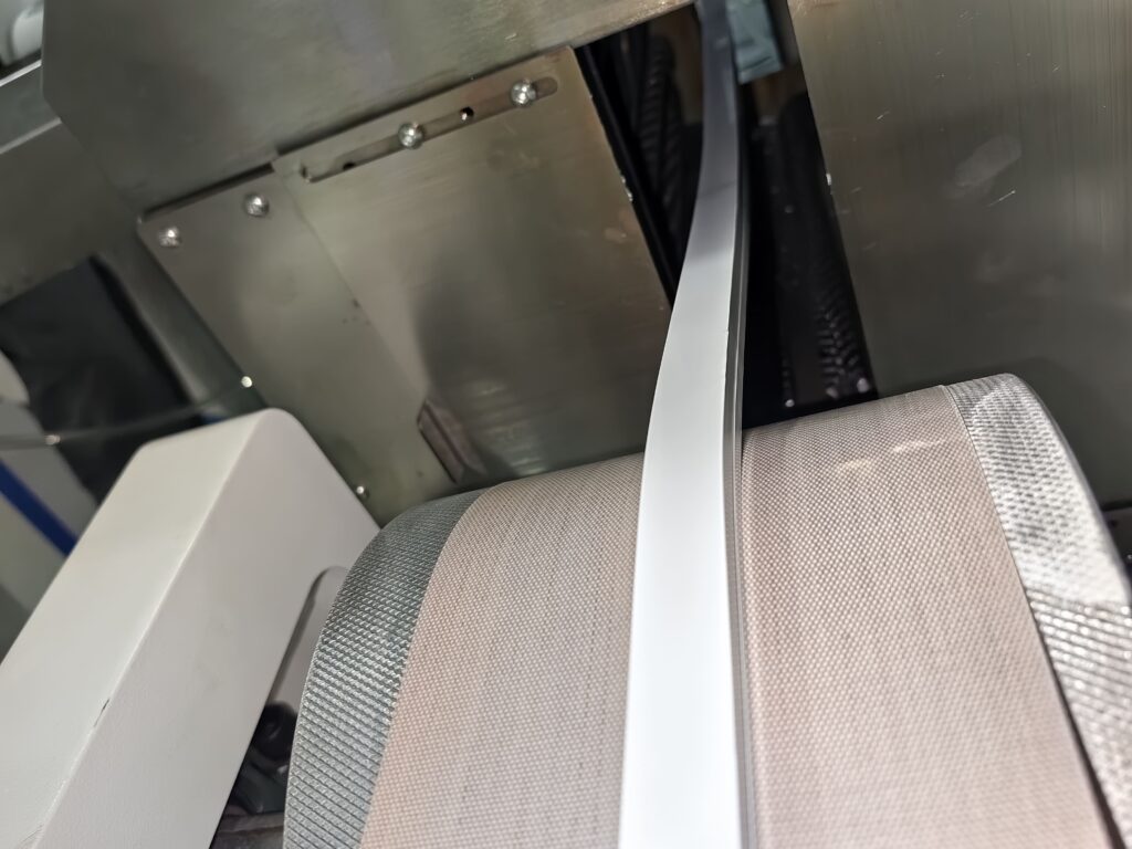 Cured silicone LED strip emerging from the high-temperature oven and traveling onto the conveyor belt.