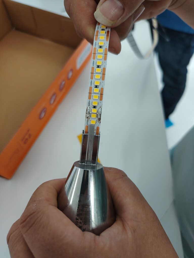Using a gauge or test mold fixture to verify the passability and alignment of a bare LED strip PCB.