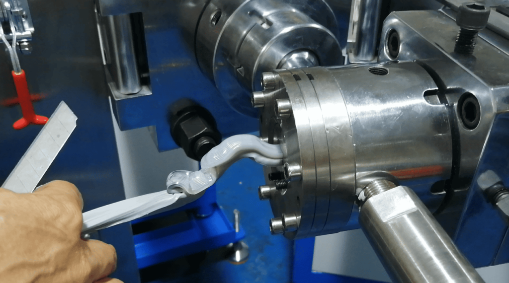 Defective silicone LED strip seal extruding unevenly from crosshead extrusion die.