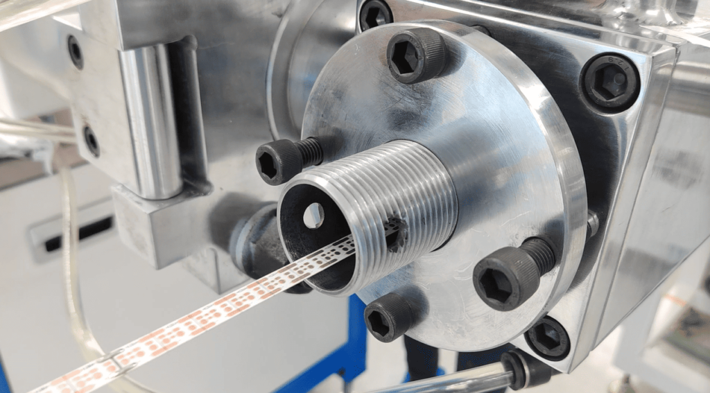 Flexible LED strip PCB being accurately fed into the silicone rubber extrusion crosshead mold.