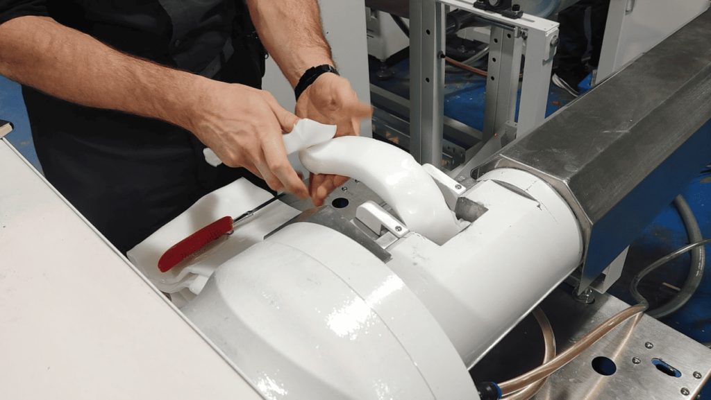 Operator manually feeding a solid silicone rubber bar into the extruder machine's hopper.