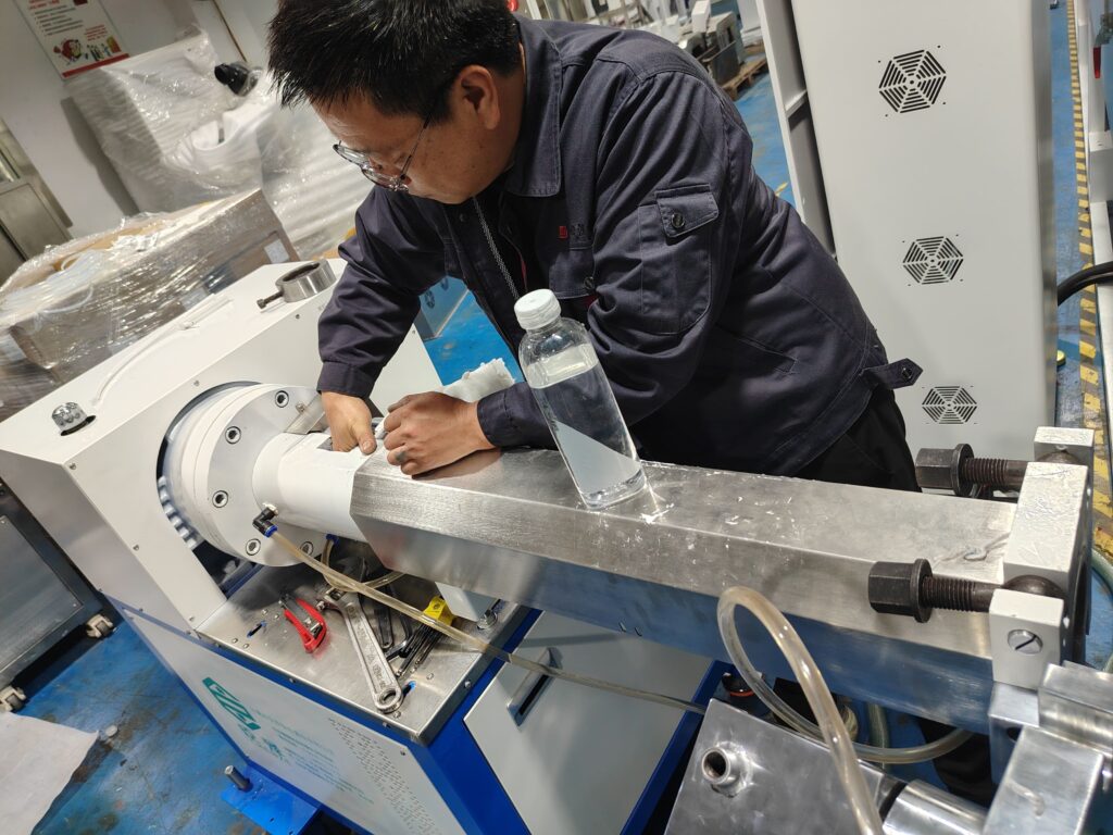 Technician carefully cleaning the interior chamber and screw of the extruder barrel.