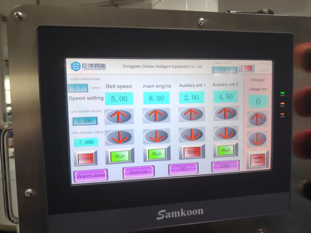 Close-up of the extrusion machine's touchscreen control panel interface during operation.