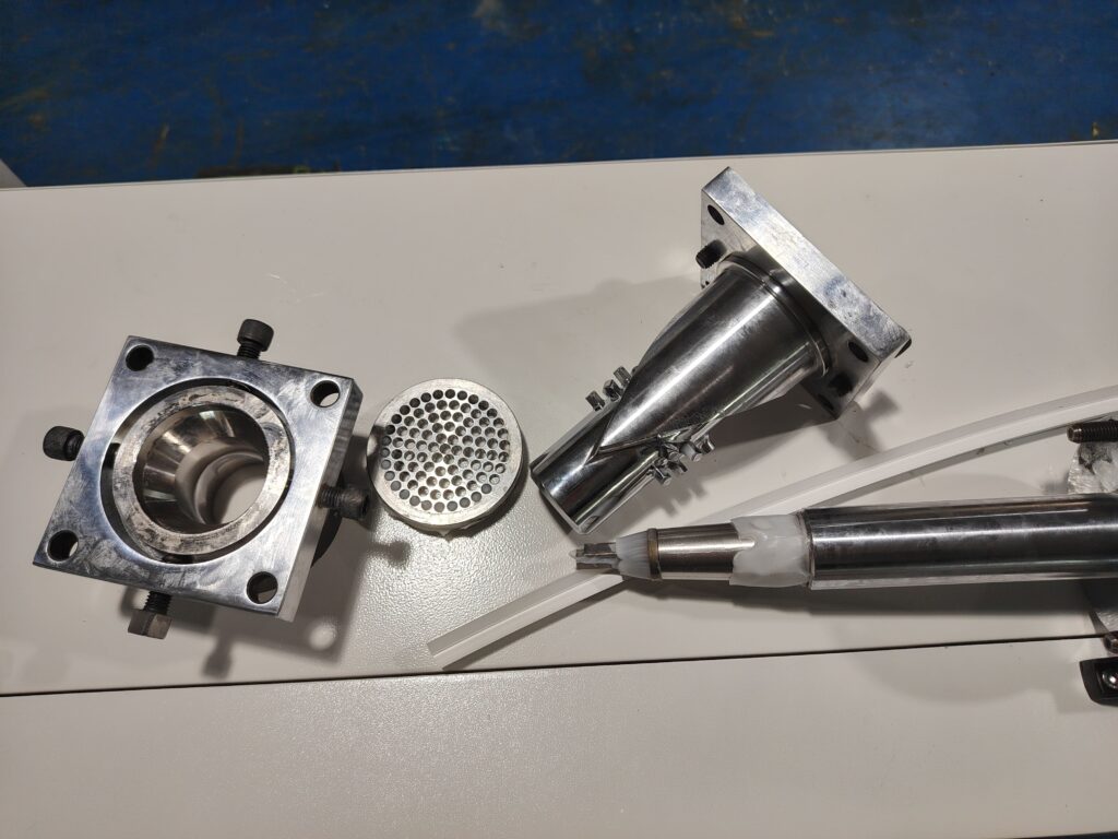 All components of a disassembled extrusion mold set laid out in order on a workbench.