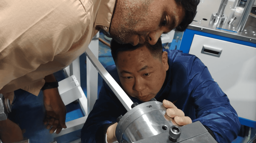 Our engineer intently observes the extruding strip while the customer closely watches and listens.