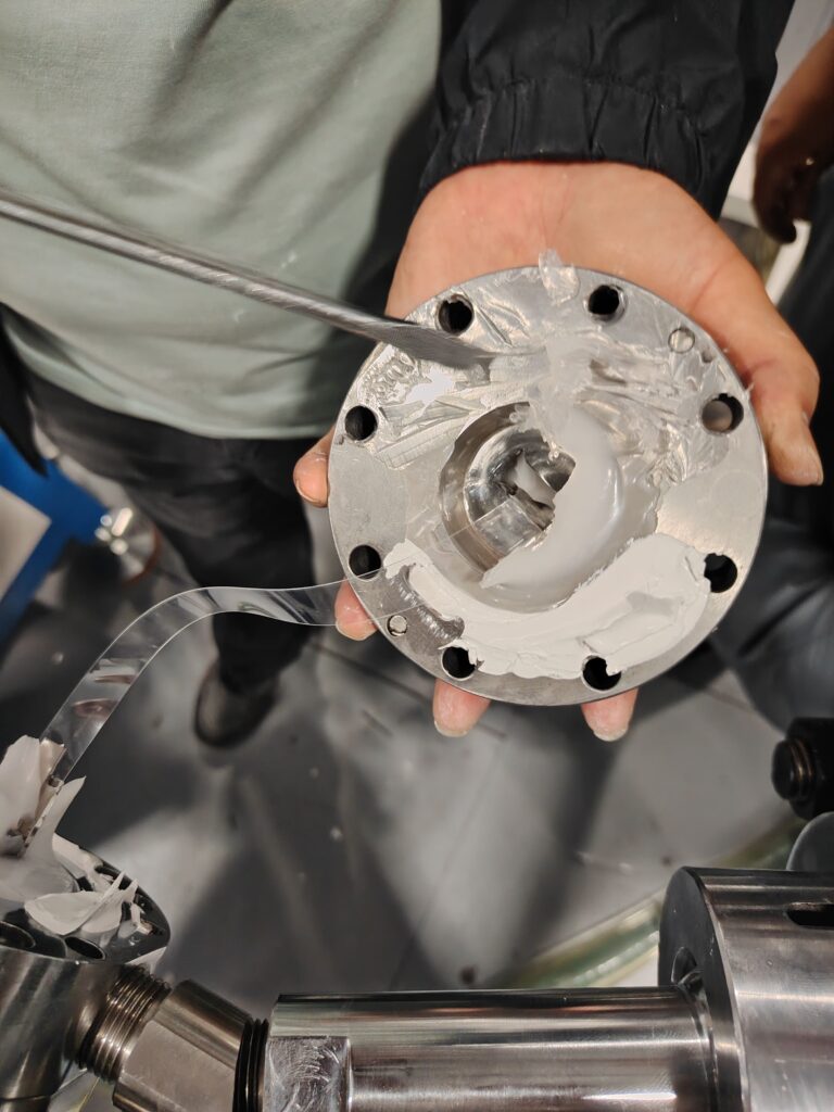 Worker holding a disassembled inner extrusion mold component (core pin) for cleaning