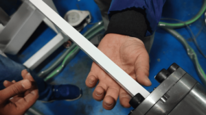 Quality control technician inspecting the profile of a freshly extruded silicone rubber strip exiting the mold.