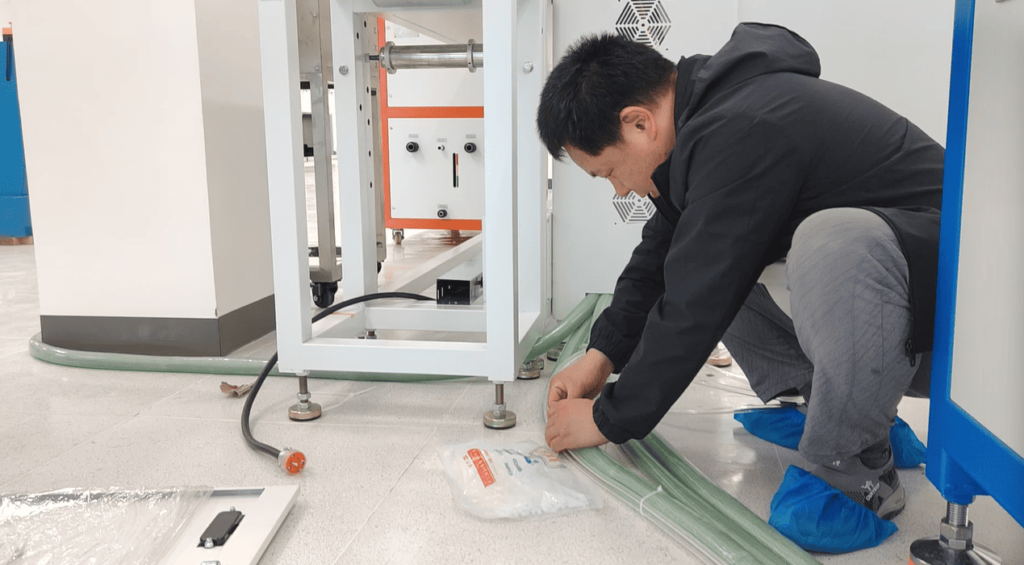 Technicians laying out and positioning the chiller unit and routing main power cables for the extrusion line.