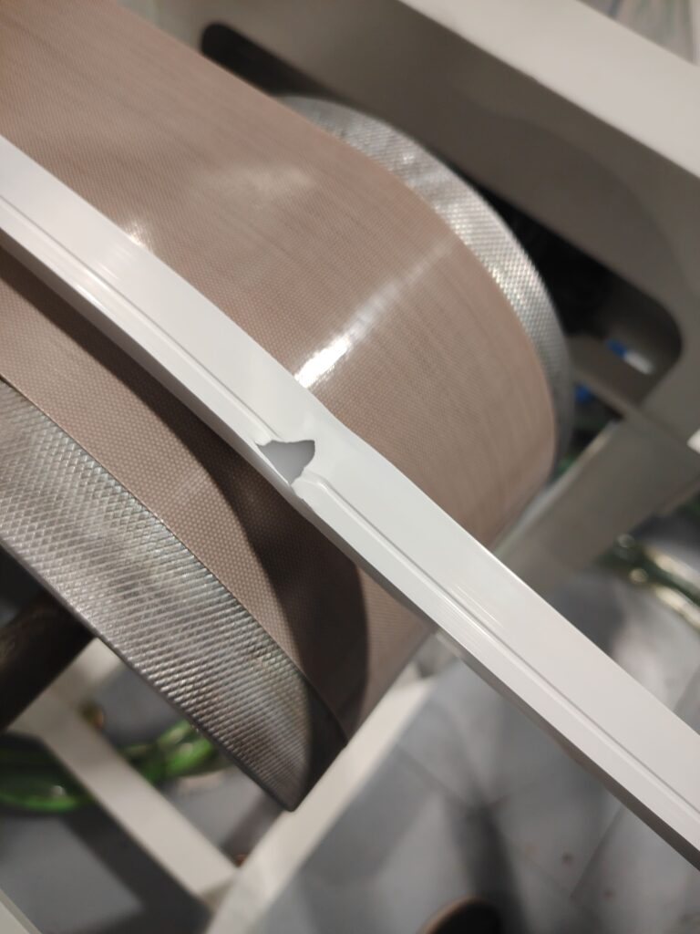 A visible gap or separation in the silicone material on an LED strip traveling down the conveyor.