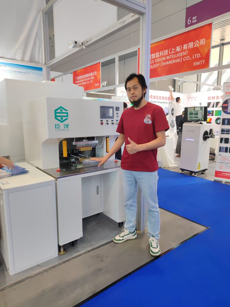 Our engineer standing with the LSR injection molding machine for end caps at an industry exhibition.