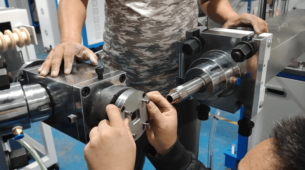 Technician assembling the outer housing and die plates of the extrusion crosshead mold.