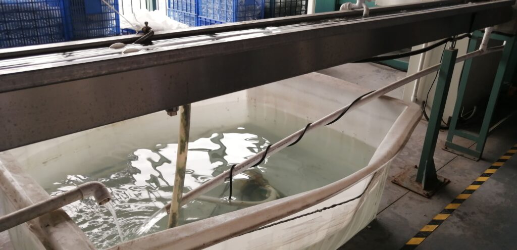 A PVC water cooling channel and a large water tank situated beneath an extrusion production line.