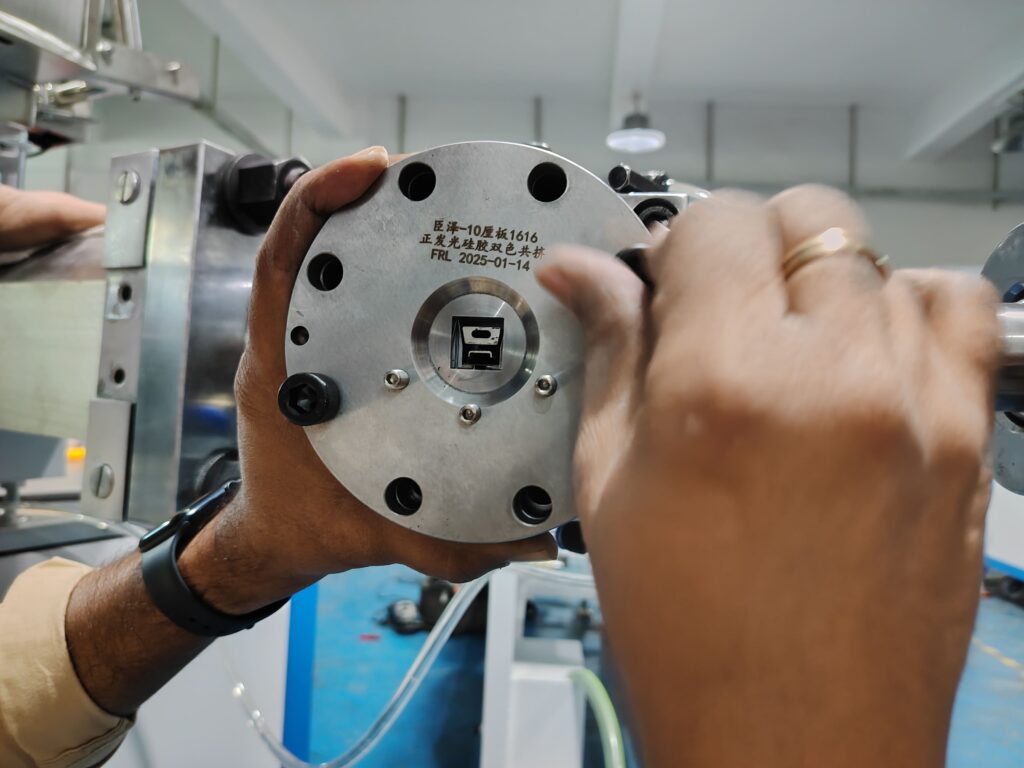 Technician adjusting an extrusion mold with a laser-etched date code "20250114" visible on its surface.