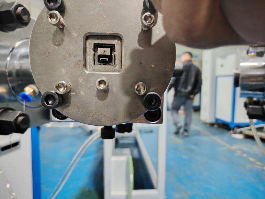 Front operational view of a silicone extrusion crosshead mold installed on an LED strip production line.