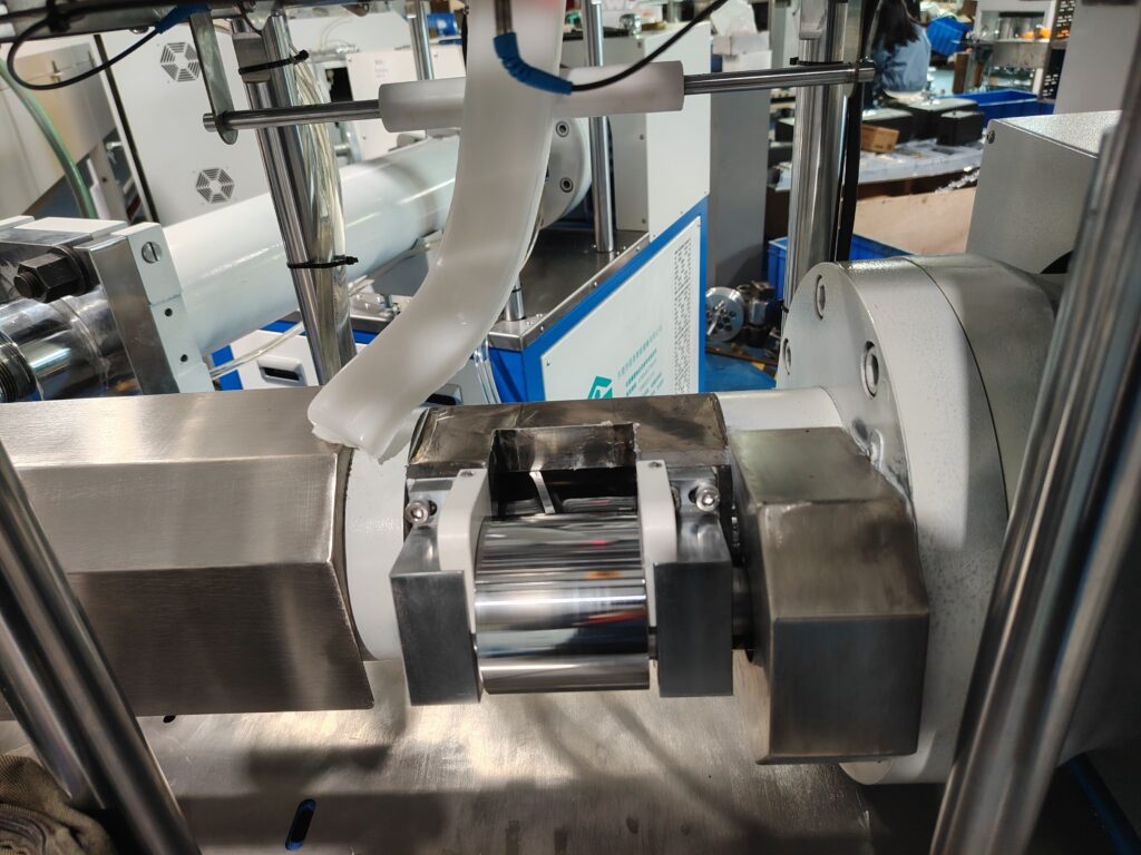 A pre-cut silicone rubber bar dropping from the discharge chute of an automatic feeding machine.