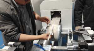 Technician inspecting the soft, uncured silicone rubber strip profile immediately after extrusion.
