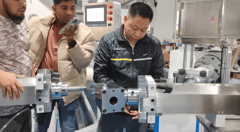 Customer recording a video on their phone as our engineer begins assembling the extrusion mold.