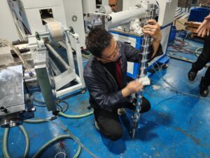 Technician cleaning the extruder screw using a specialized abrasive cloth