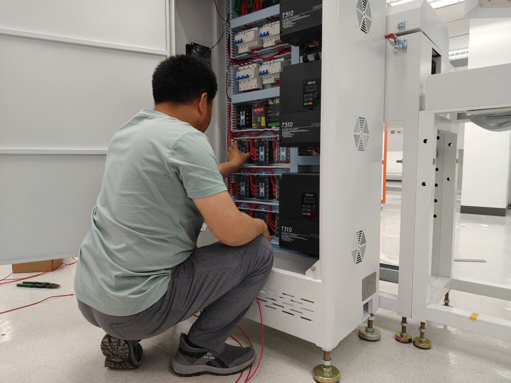Technician completing the final wiring connections for the main control panel of a silicone extrusion line.