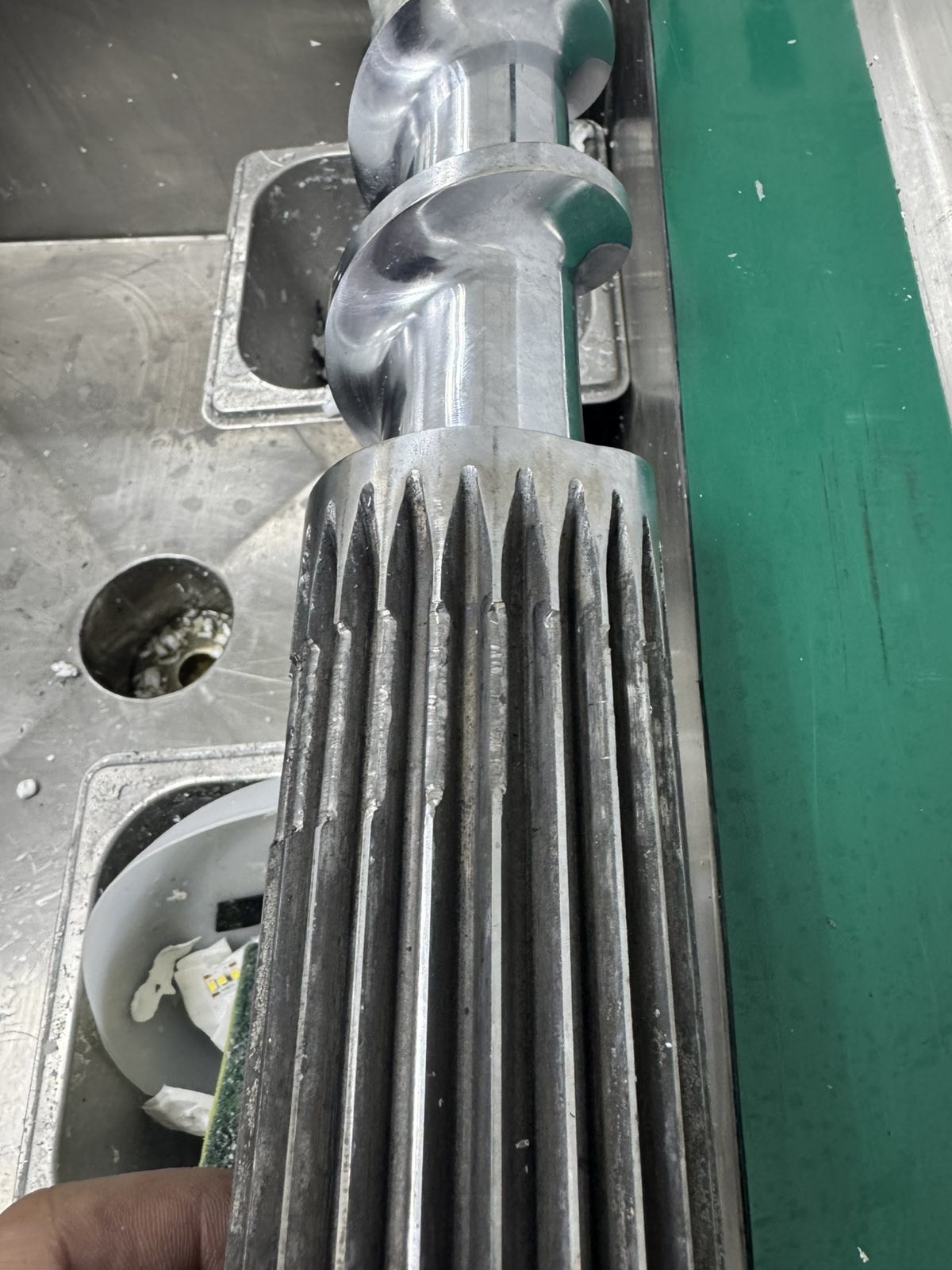 Detailed view of an LED silicone extrusion screw showing crushed splines and metal surface damage.